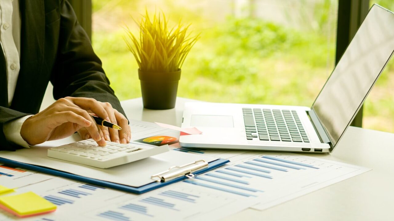 businessman in finance and calculating calculators and analyzing graphs on real estate investment costs and other tax systems