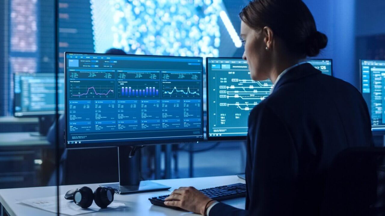 confident female data scientist works on personal computer in big infrastructure control and monitoring room