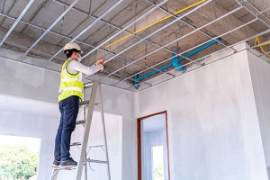 electrician wearing a mask installing laying electrical cables on the ceiling