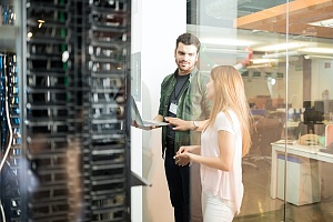 it security worker talking to an office worker about penetration testing next to server racks
