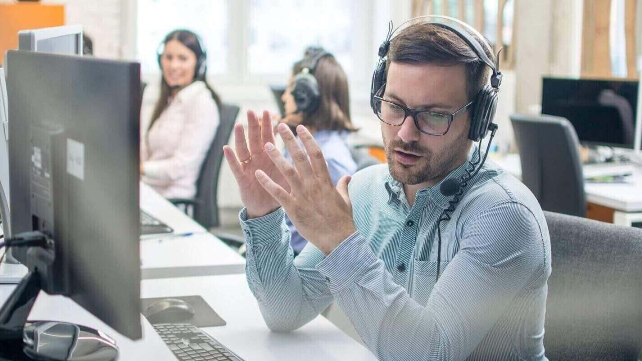 male technical support agent trying to explain something to a client while using hands