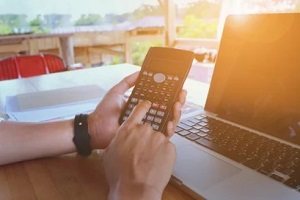 man on calculator near laptop
