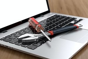 screwdriver and wrench on a laptop symbolizing managed it services in queens new york