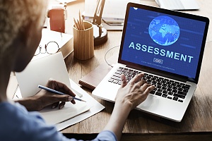 woman at her desk with her laptop screen on an it assessment web page for it security for her business